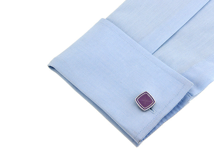 Close-up of a light blue shirt cuff with a purple gemstone cufflink on a white background