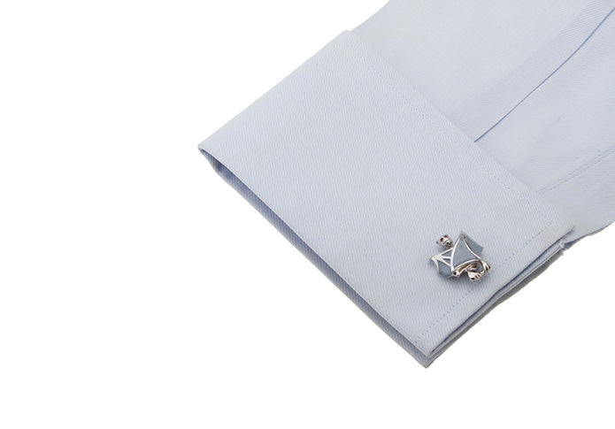 Cufflink on a light blue shirt sleeve with a white background