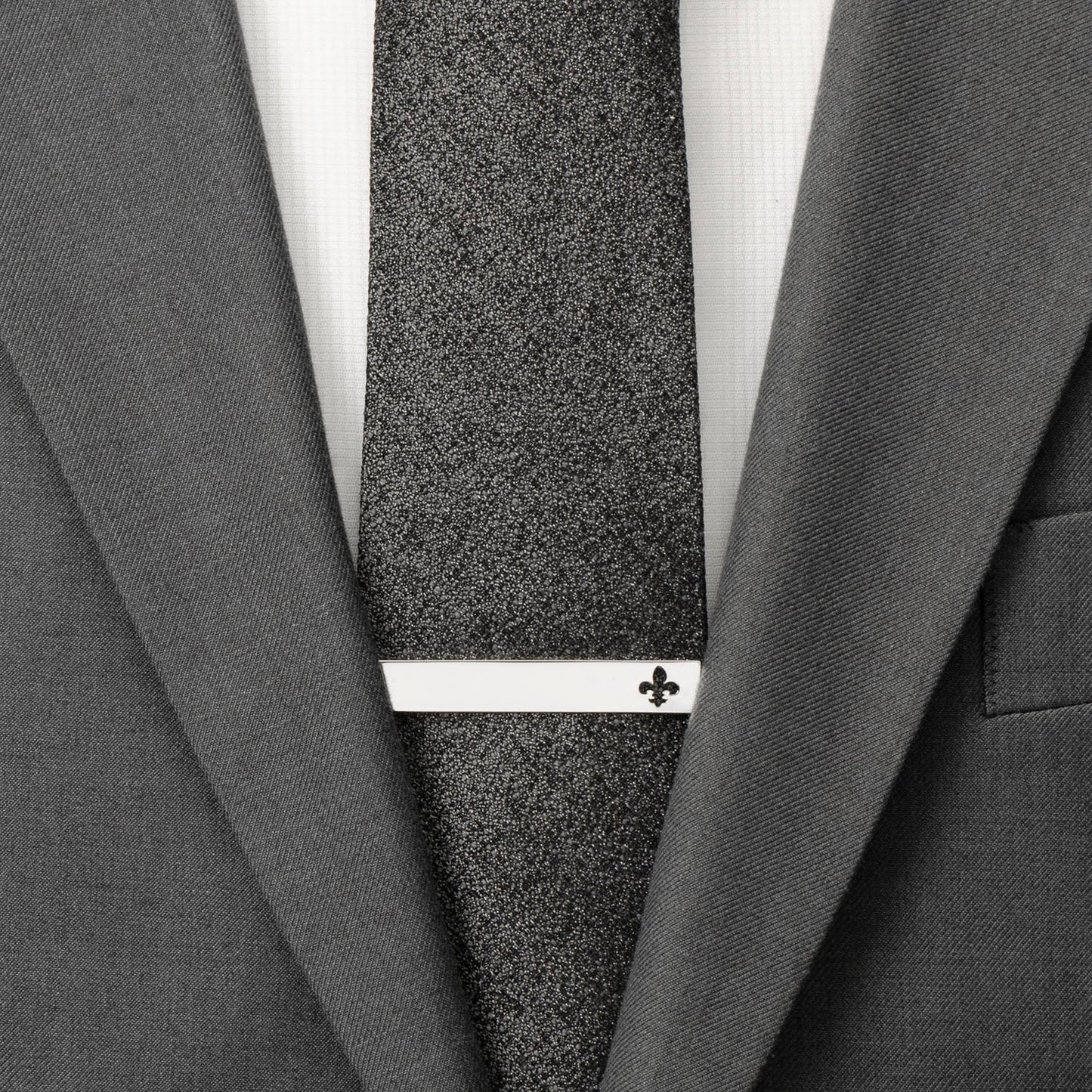 Gray textured tie with a white clasp on a gray suit jacket