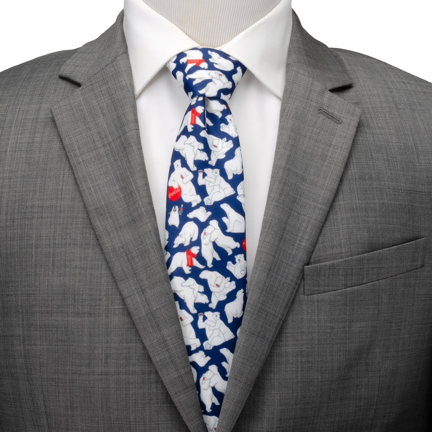 Gray suit jacket with a white shirt and blue tie featuring polar bear pattern on a mannequin. Coca-Cola Polar Bear navy blue men’s tie with red scarf design