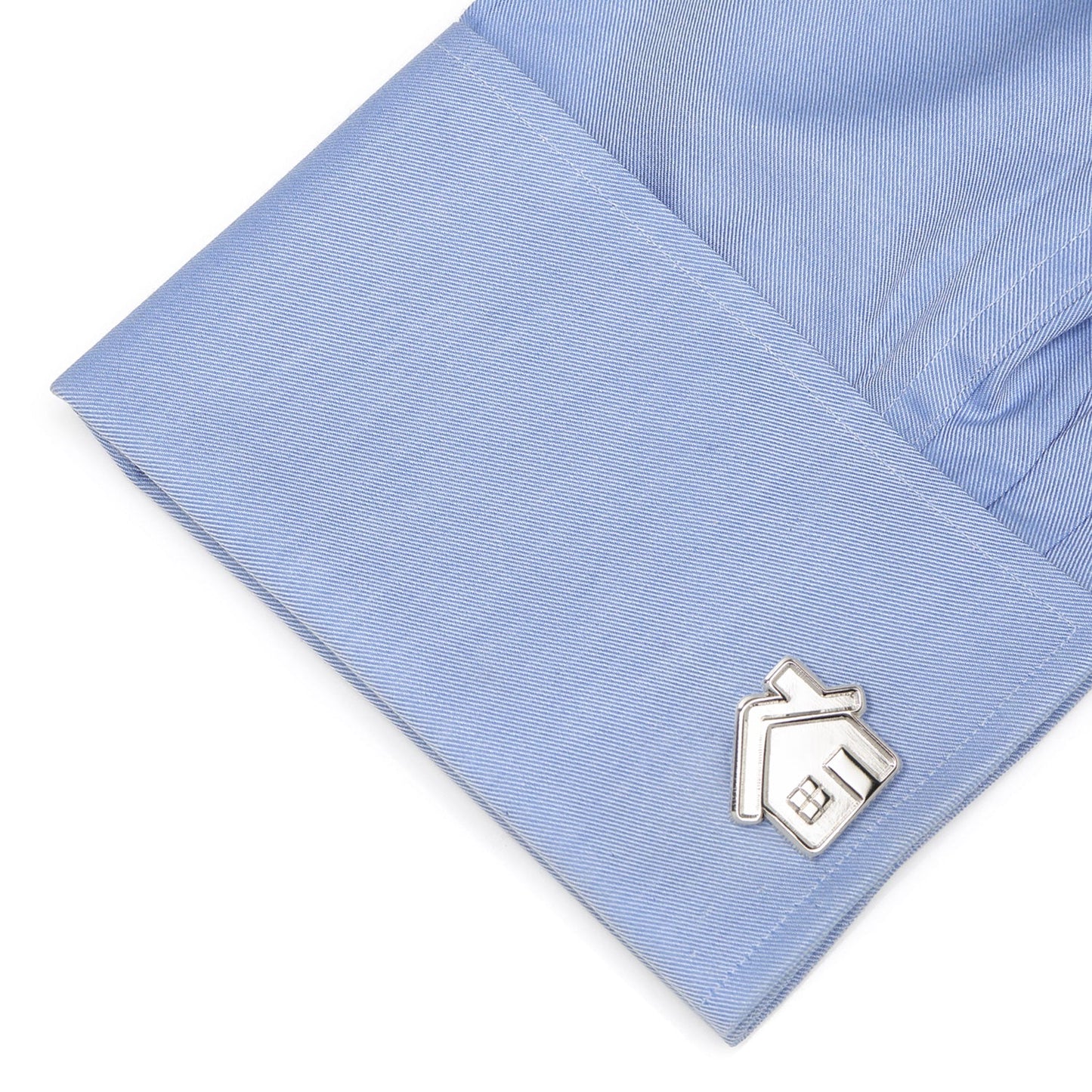 Silver house-shaped cufflink on a light blue shirt