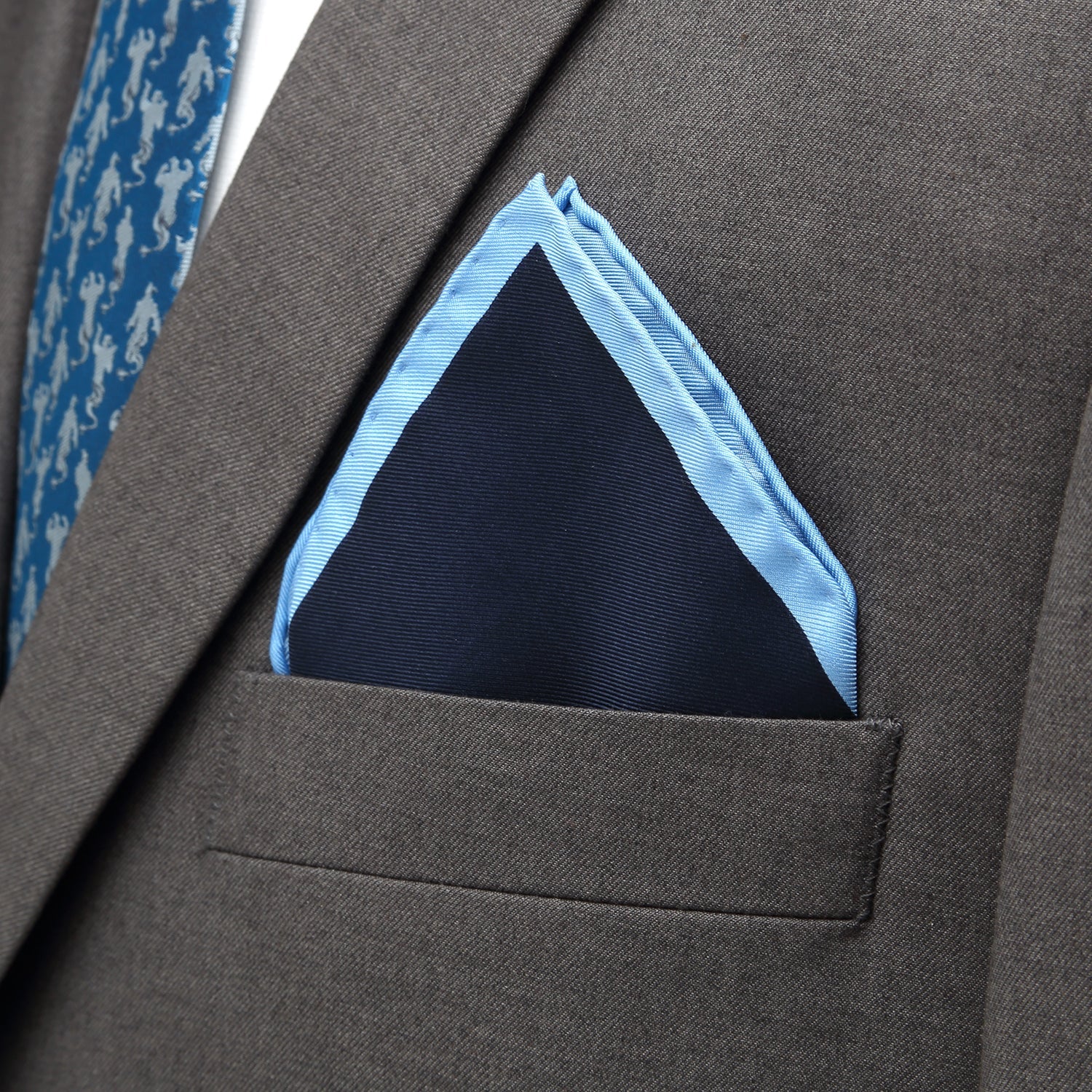 Gray suit jacket with a blue pocket square and a patterned blue tie.