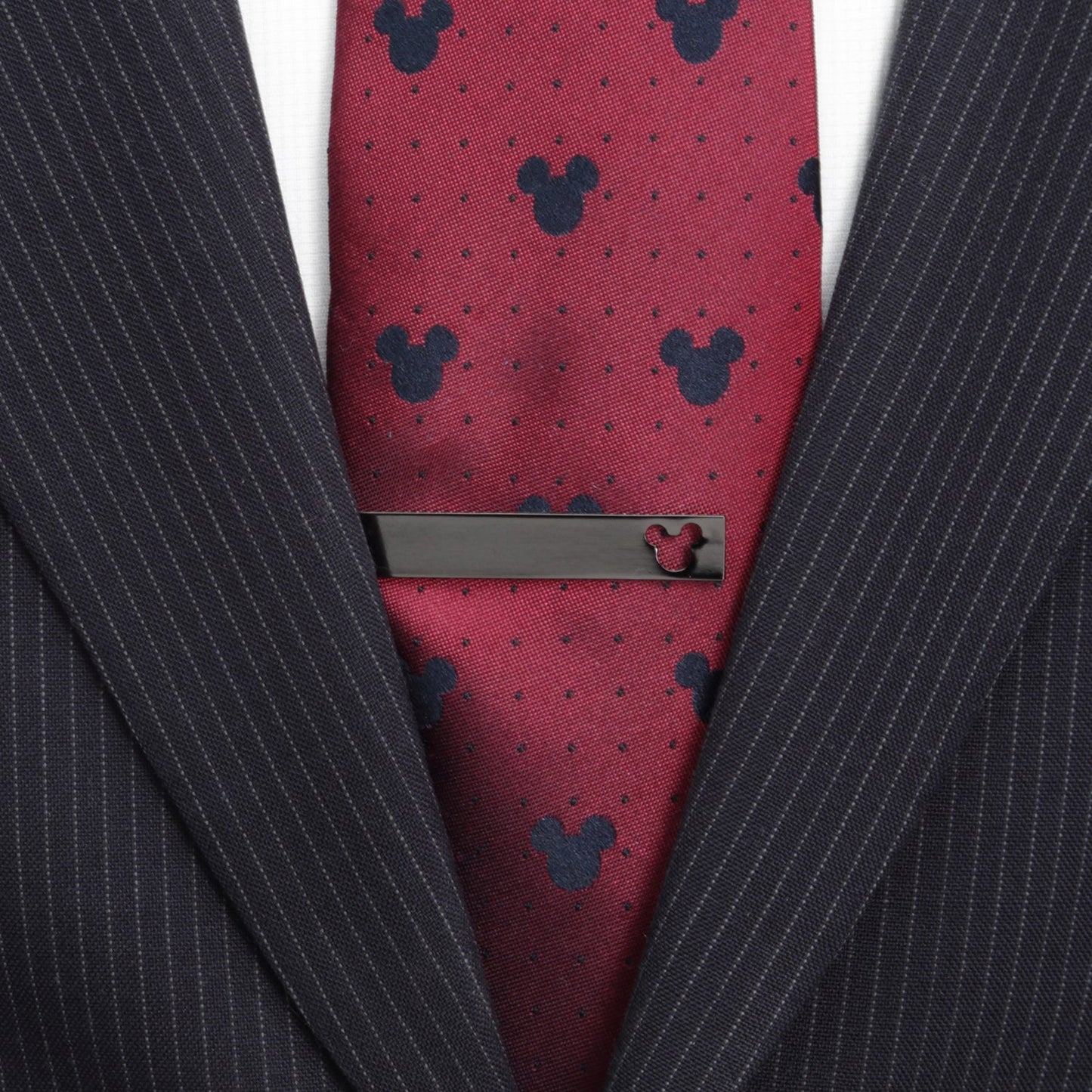 Red tie with black mickey mouse pattern and matching tie clip on a dark suit jacket.