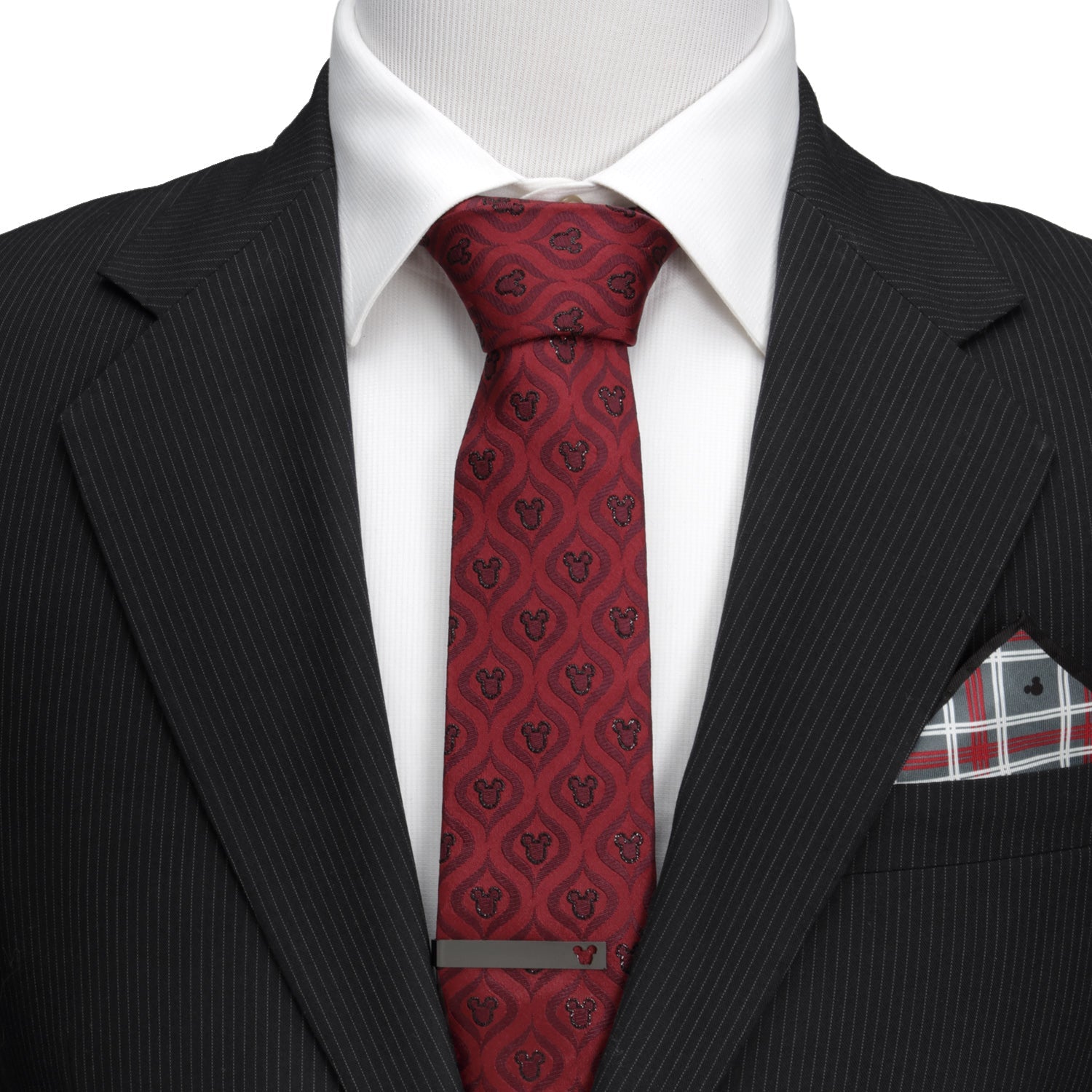 Black suit with a red patterned tie and plaid pocket square on a white background