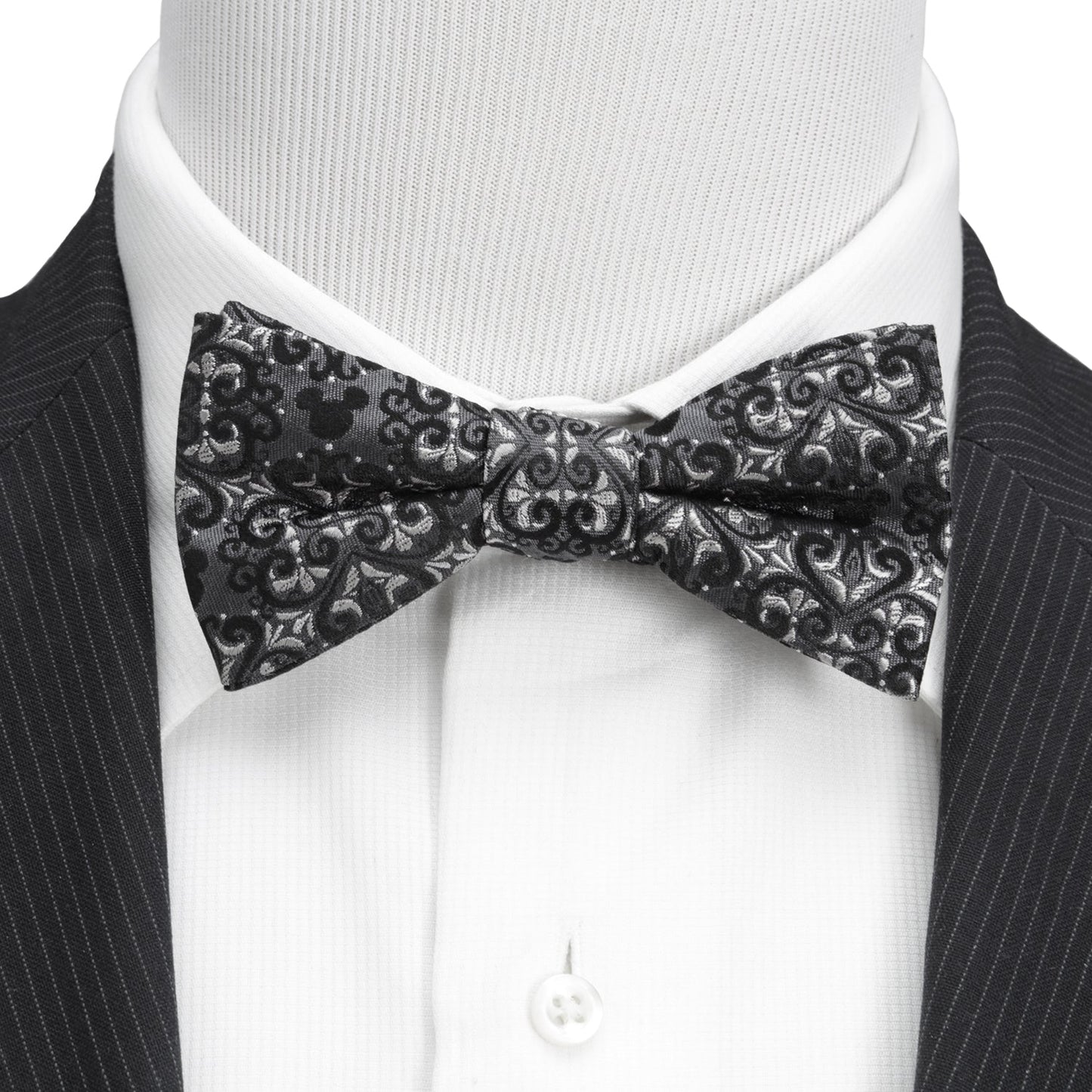 Black patterned bow tie worn with a black suit and white shirt.