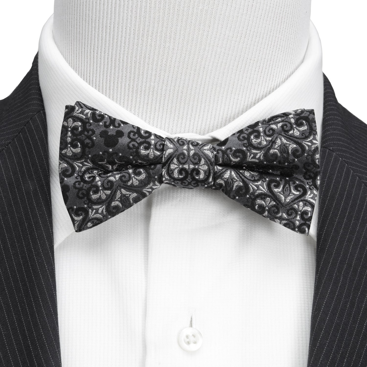 Black patterned bow tie worn with a black suit and white shirt.