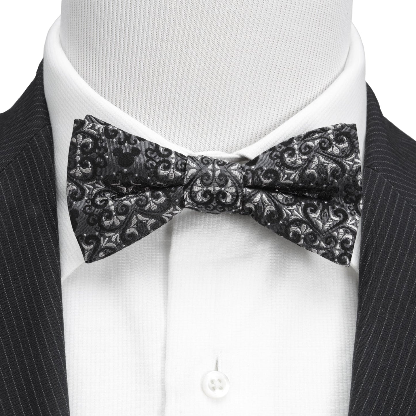 Black patterned bow tie on a mannequin with a black suit and white shirt. Mickey Mouse