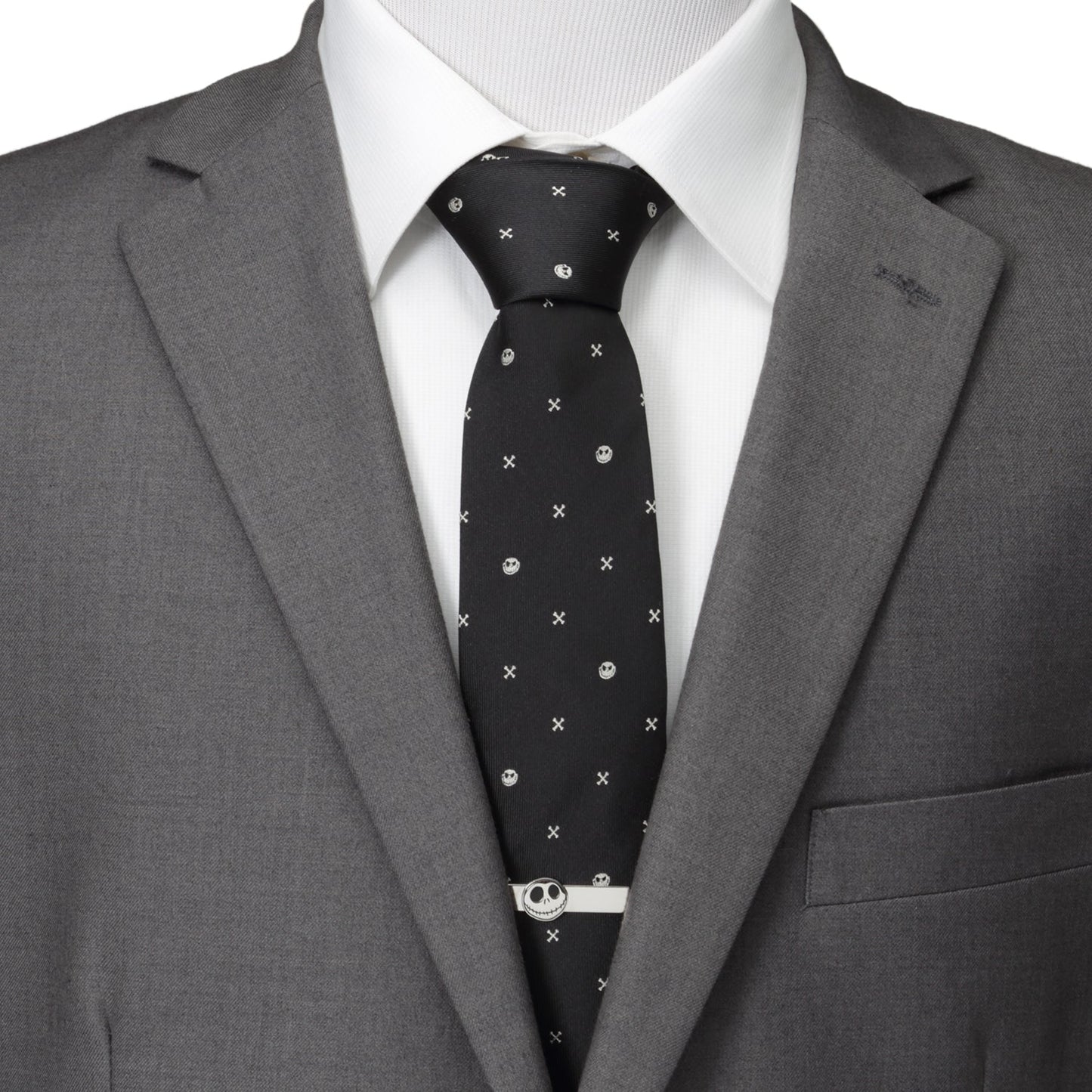 Gray suit jacket with a white shirt and black patterned tie on a mannequin. Disney Jack Skellington black silk tie with crossbones pattern