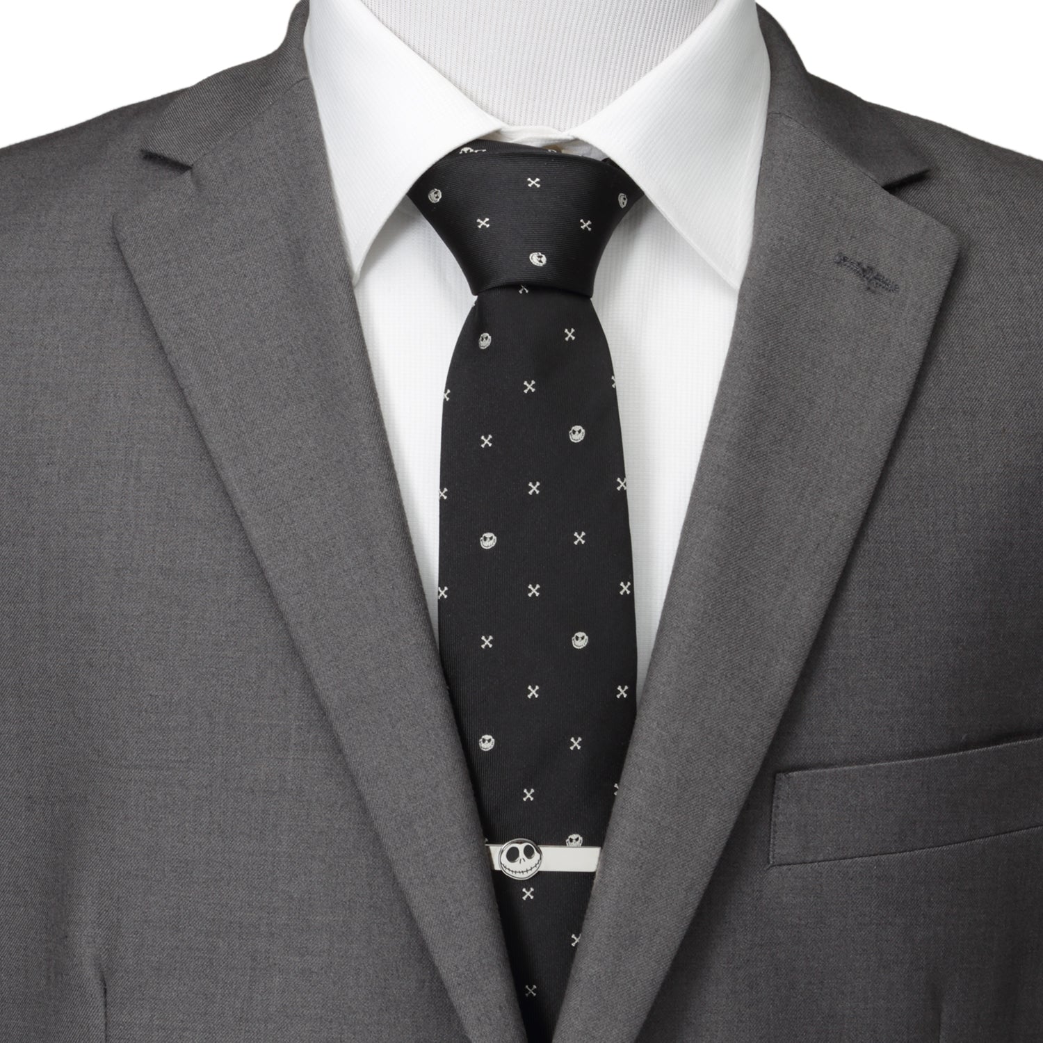 Gray suit jacket with a white shirt and black patterned tie on a mannequin. Disney Jack Skellington black silk tie with crossbones pattern