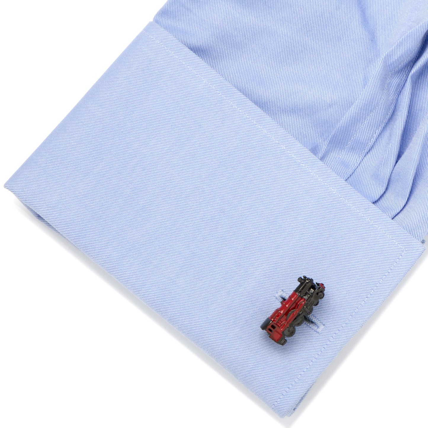 Close-up of a blue shirt cuff with a red and black train-shaped cufflink.