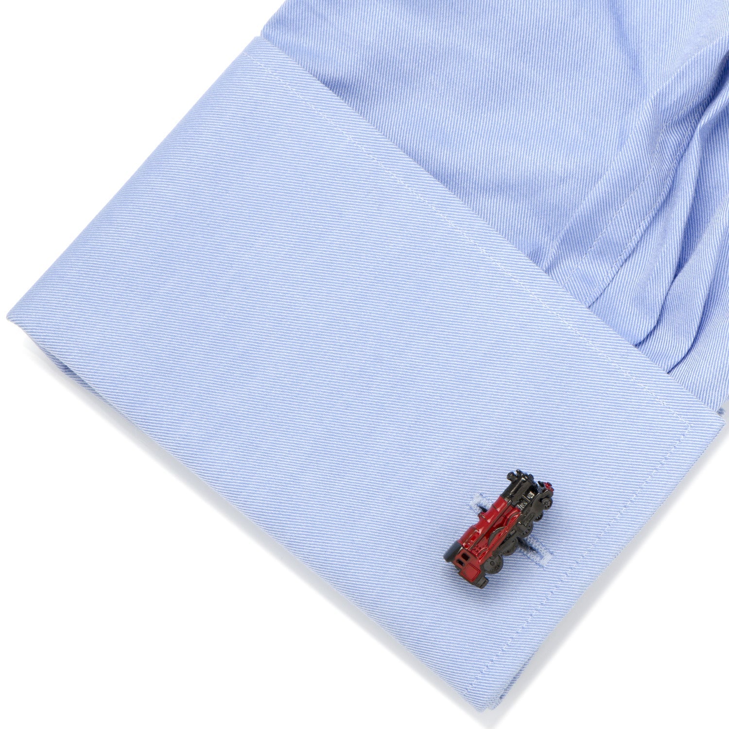 Close-up of a blue shirt cuff with a red and black train-shaped cufflink.
