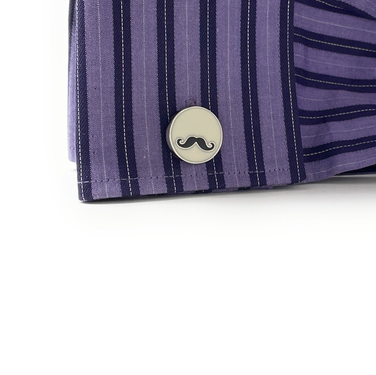 Close-up of a purple striped shirt with a decorative button featuring a mustache design on a white background.