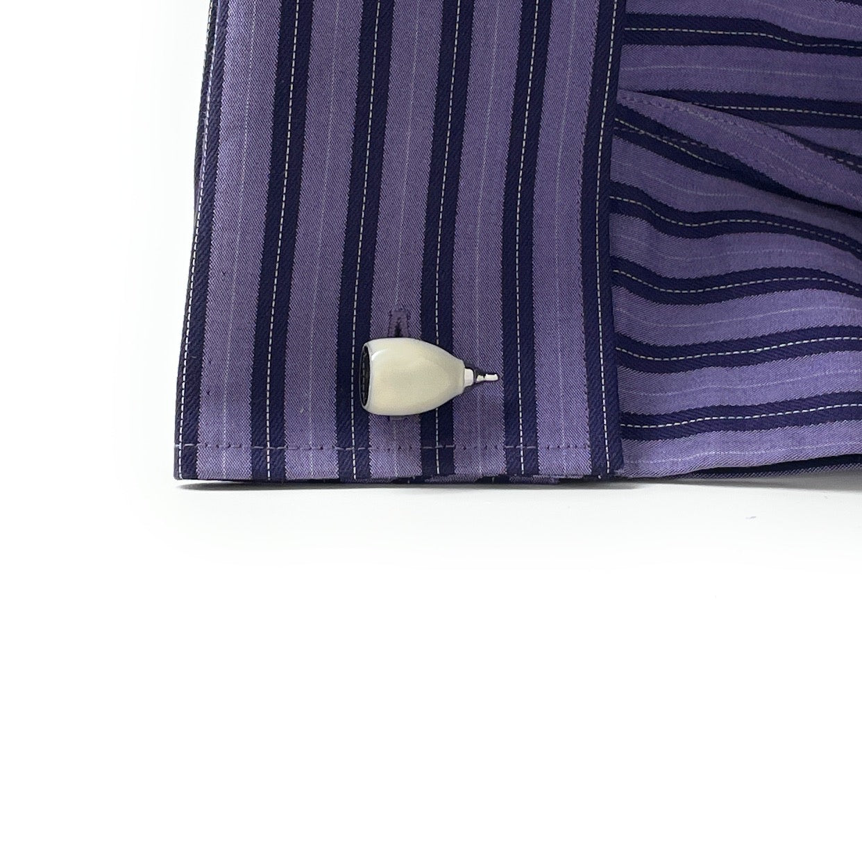 Close-up of a purple striped shirt with a white button on a white background