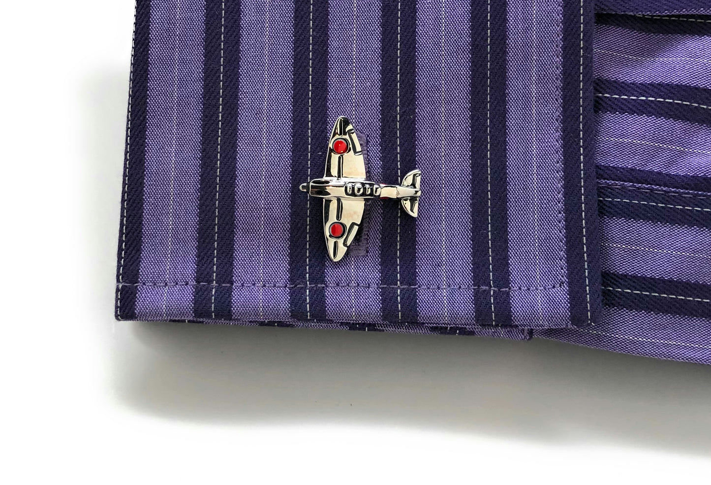 Close-up of a purple striped shirt with an airplane pin on a white background
