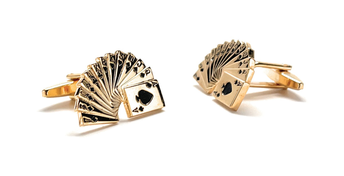 Gold cufflinks with playing card design on a white background