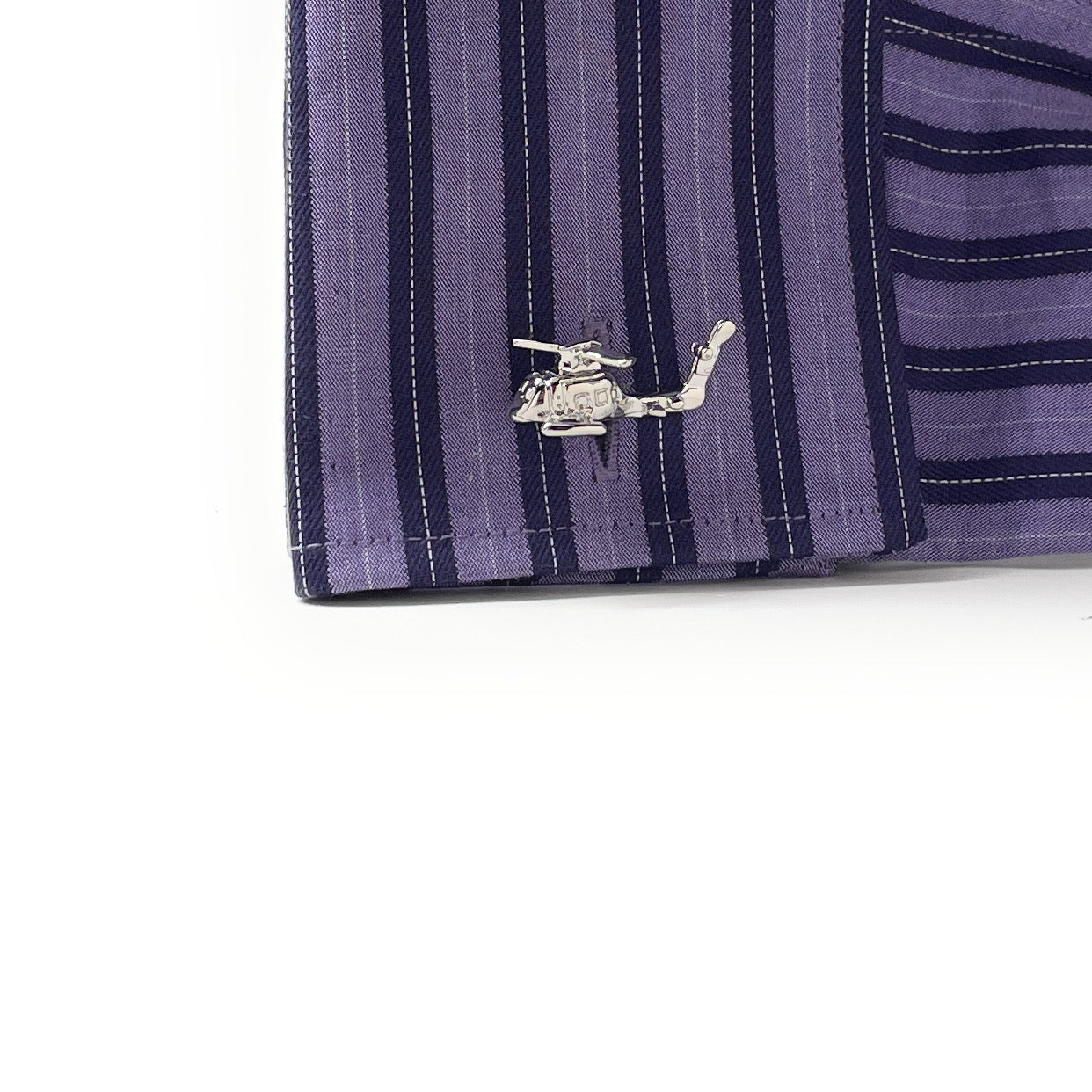 Close-up of a purple striped shirt with a helicopter cufflink on a white background