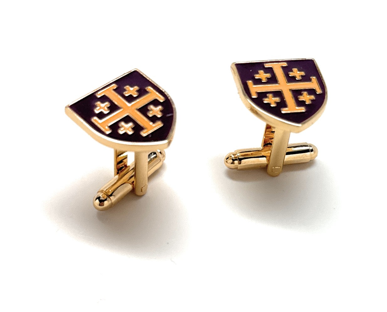 Gold and purple cufflinks with a shield design on a white background