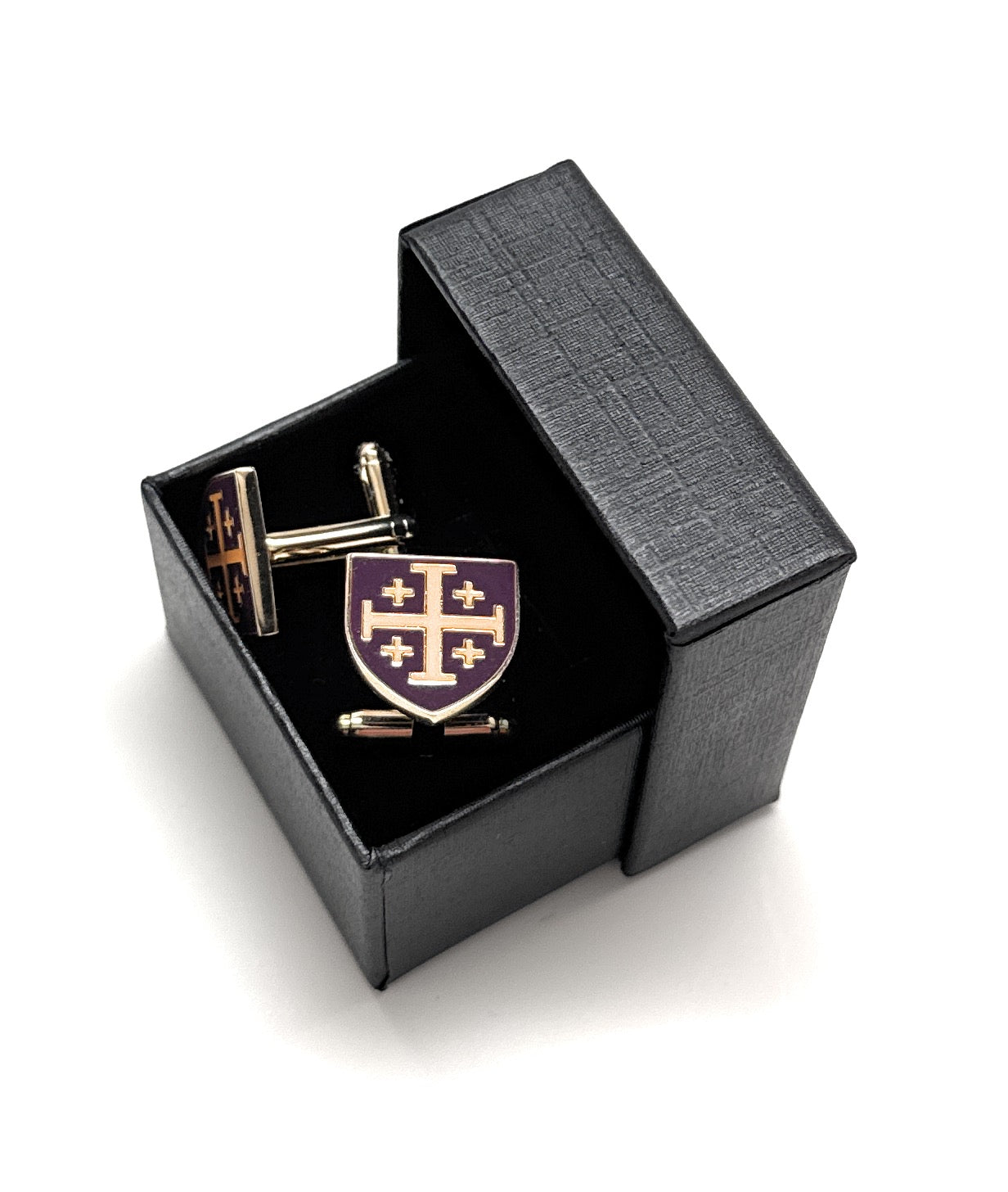 Cufflinks with a purple emblem in an open black box on a white background