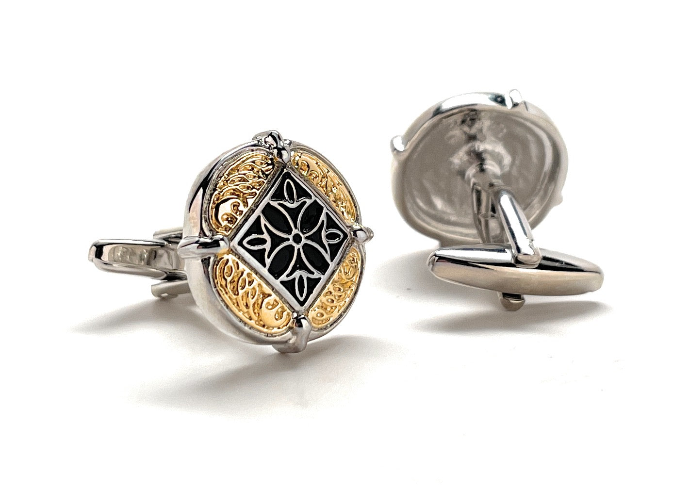 Silver and gold cufflinks with intricate design on a white background