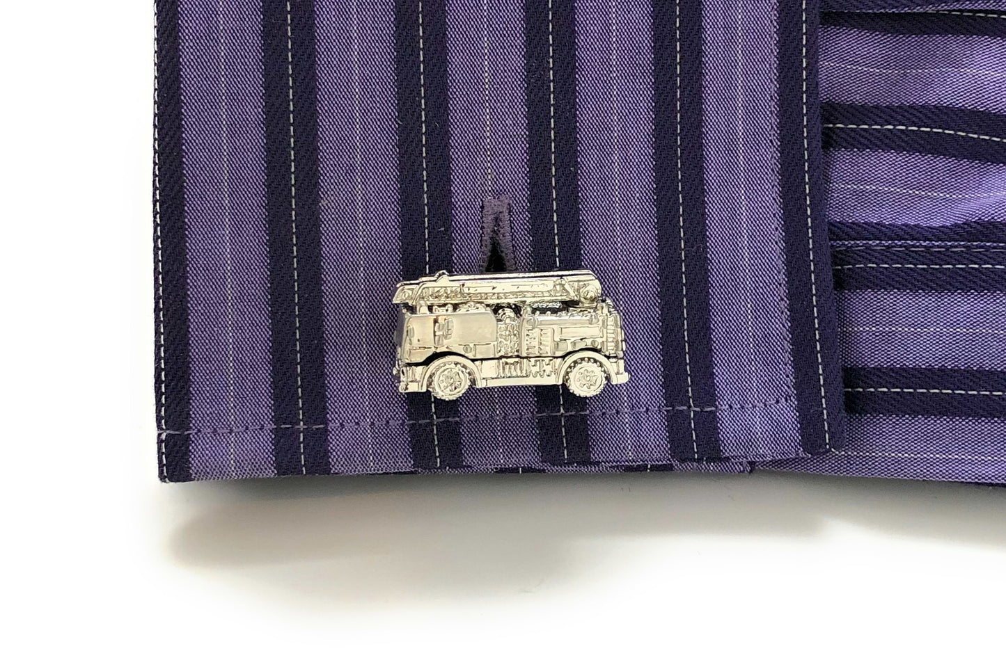 Silver truck-shaped lapel pin on a purple striped shirt
