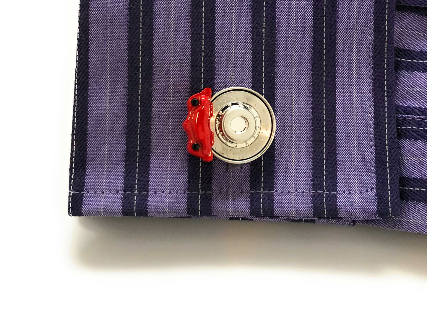 Close-up of a button on a striped shirt with a red accent