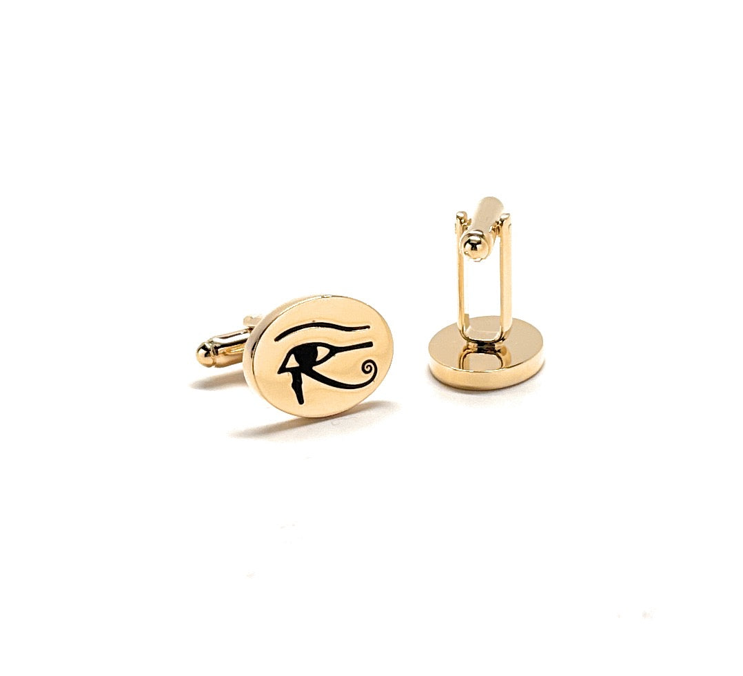 Gold cufflinks with an eye symbol on a white background