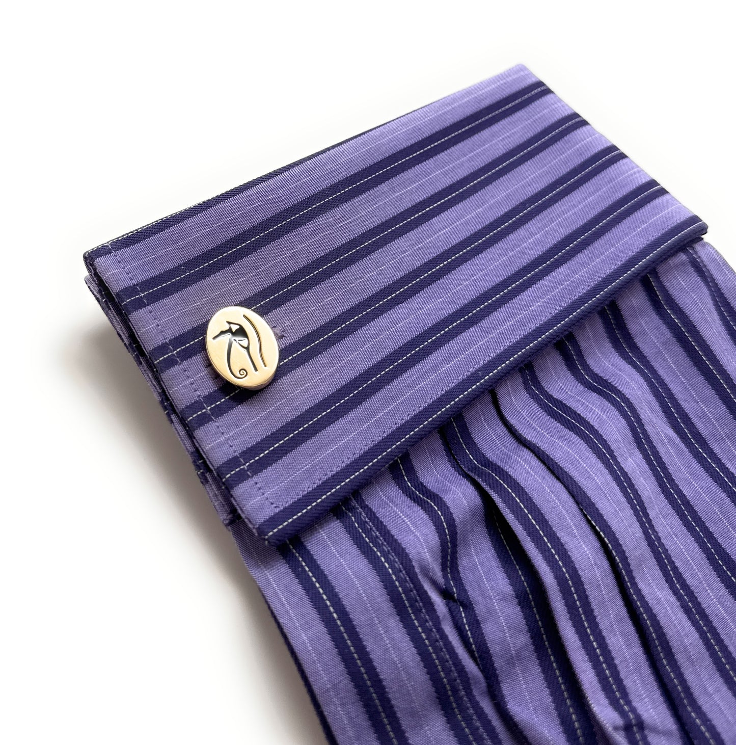 Purple striped fabric with a gold button on a white background