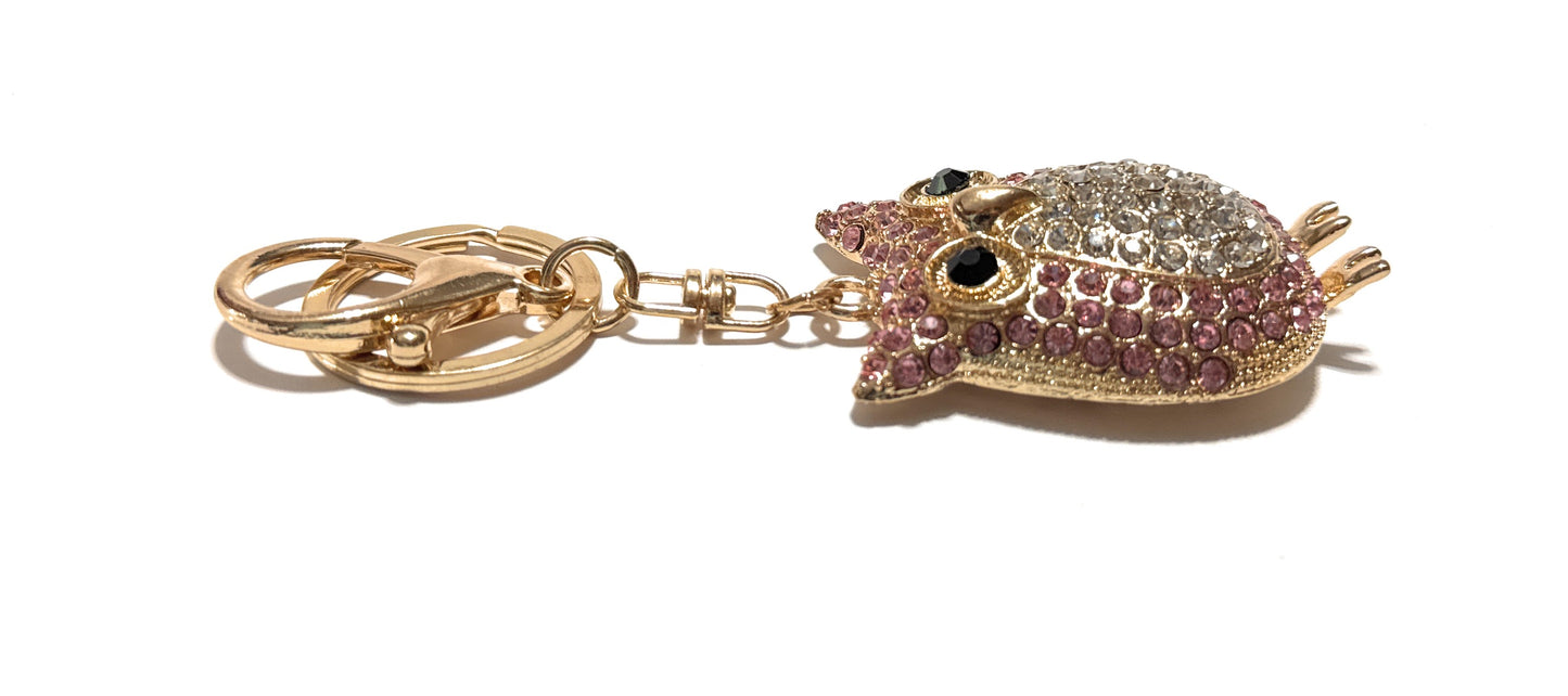Decorative keychain with a pink and gold skull design on a white background