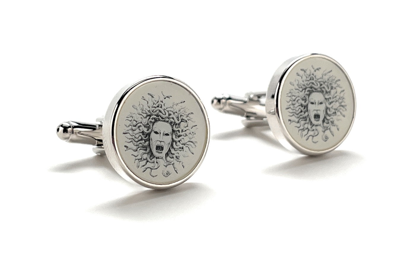 Pair of cufflinks with engraved design on a white background