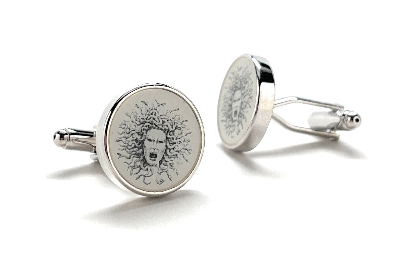 Silver cufflinks with engraved design on a white background