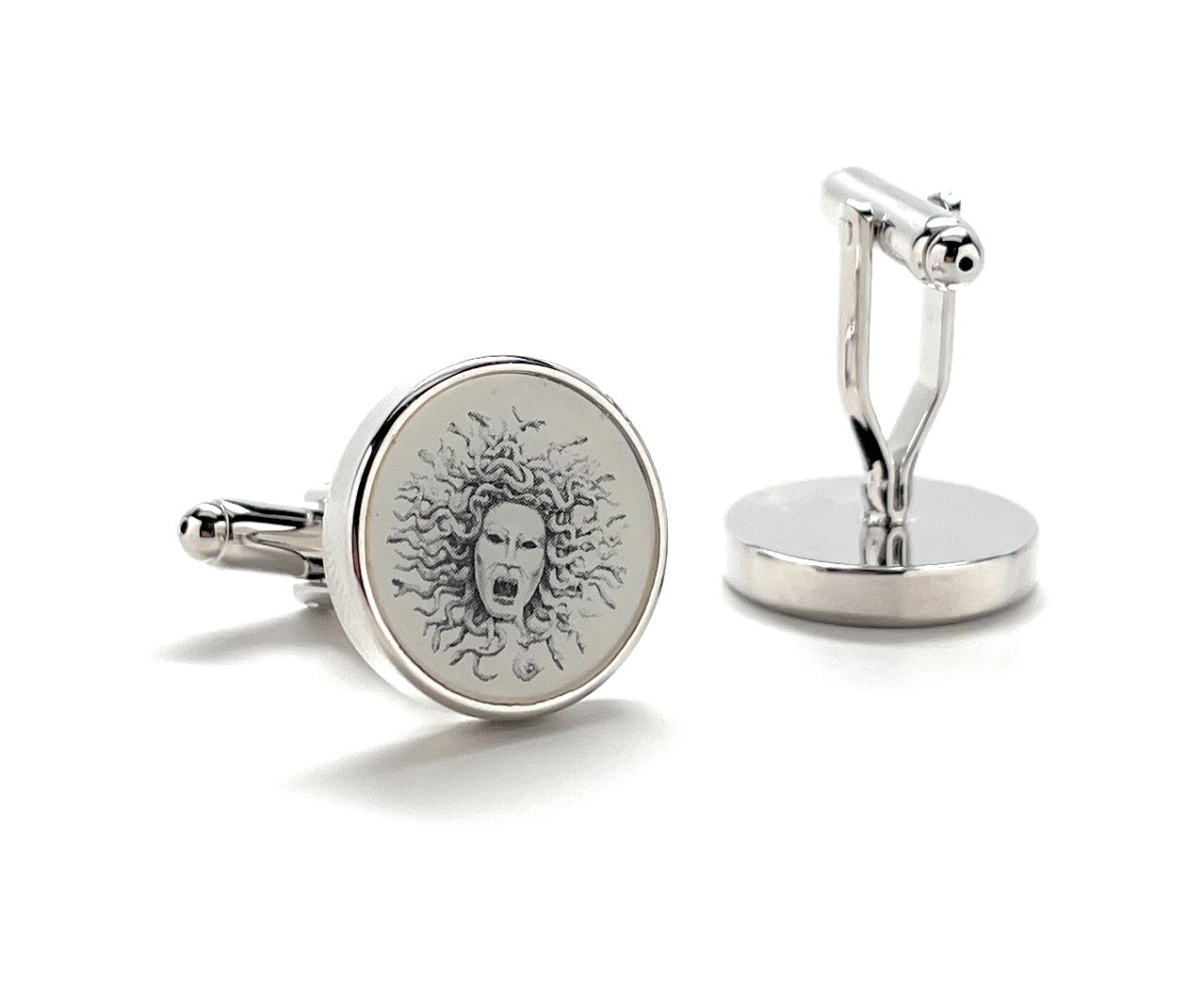 Silver cufflinks with a face design on a white background
