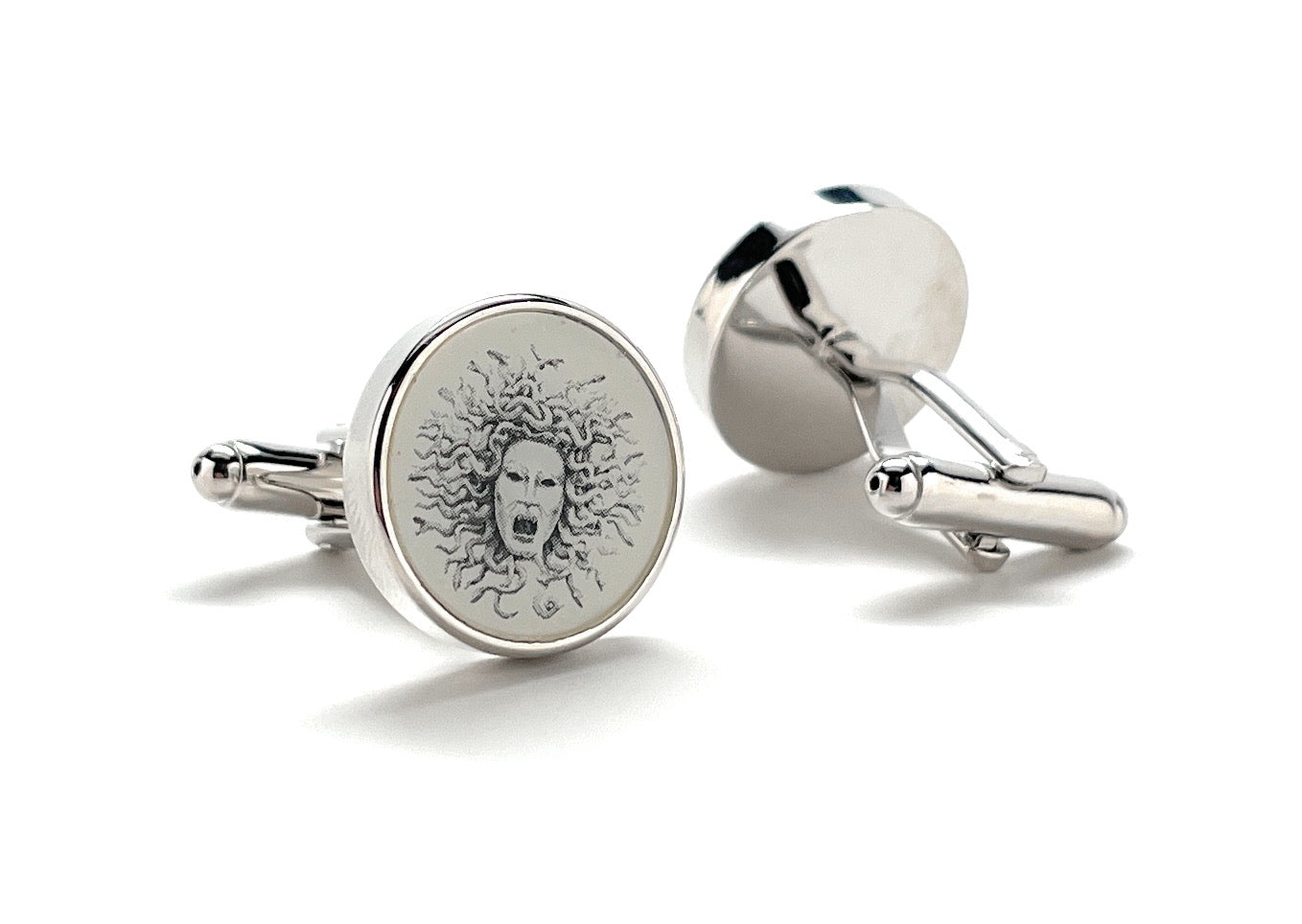 Silver cufflinks with engraved design on a white background