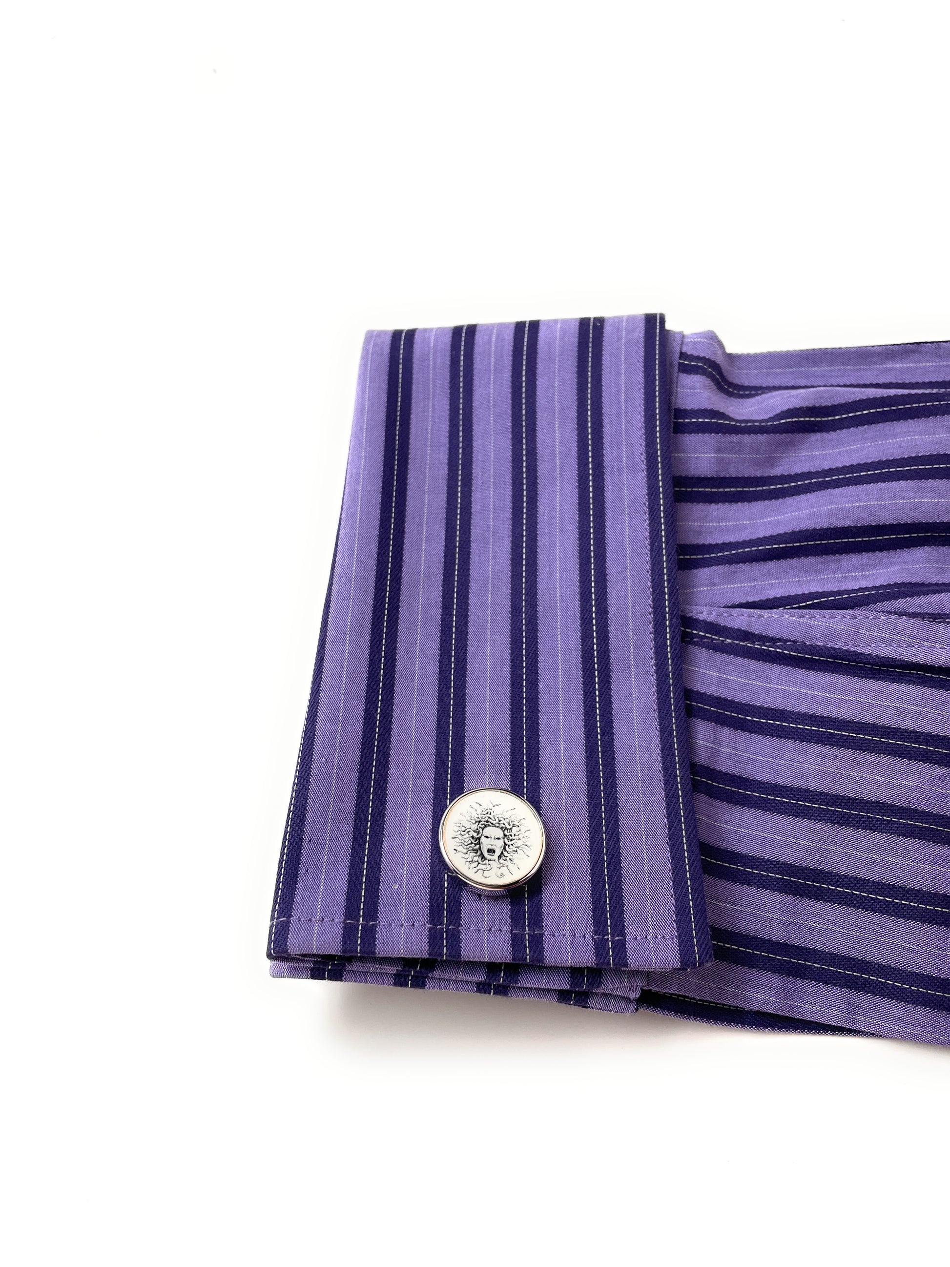 Folded purple striped shirt with a button on a white background