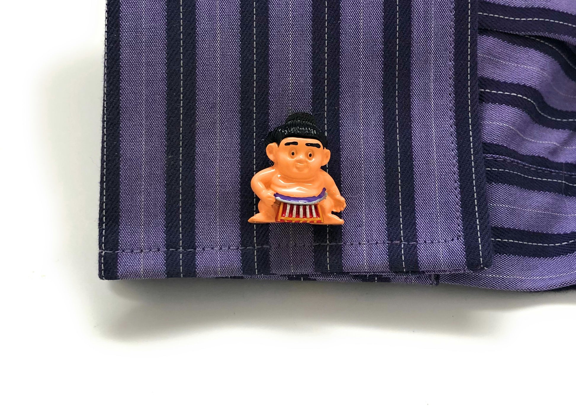 Small cartoon character on a striped fabric background
