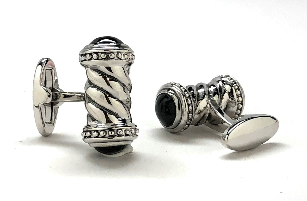 Silver cufflinks with intricate design on a white background