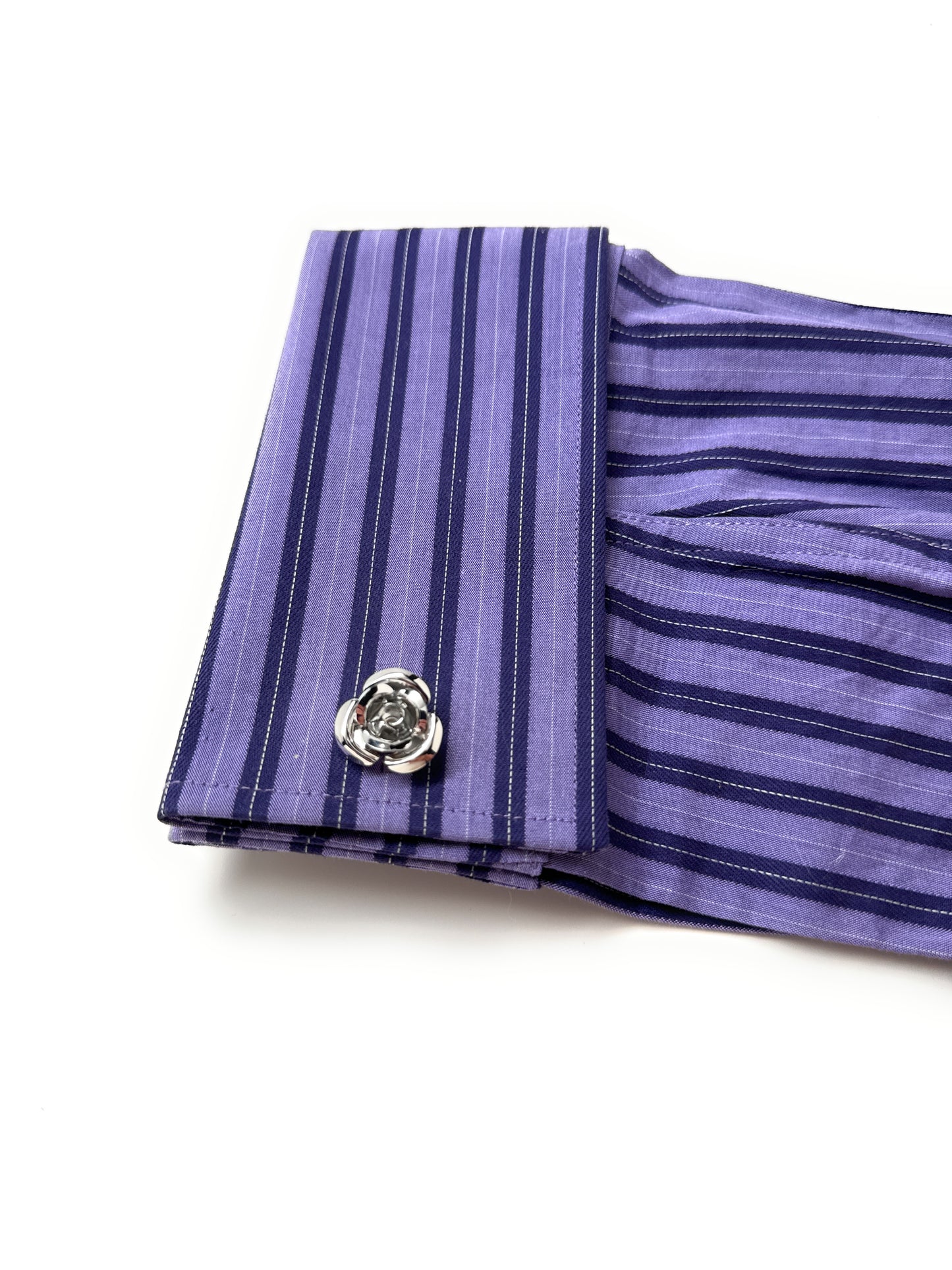 Close-up of a purple striped fabric with a floral brooch on a white background