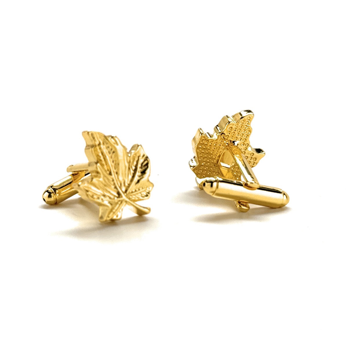 Gold maple leaf cufflinks on a white background