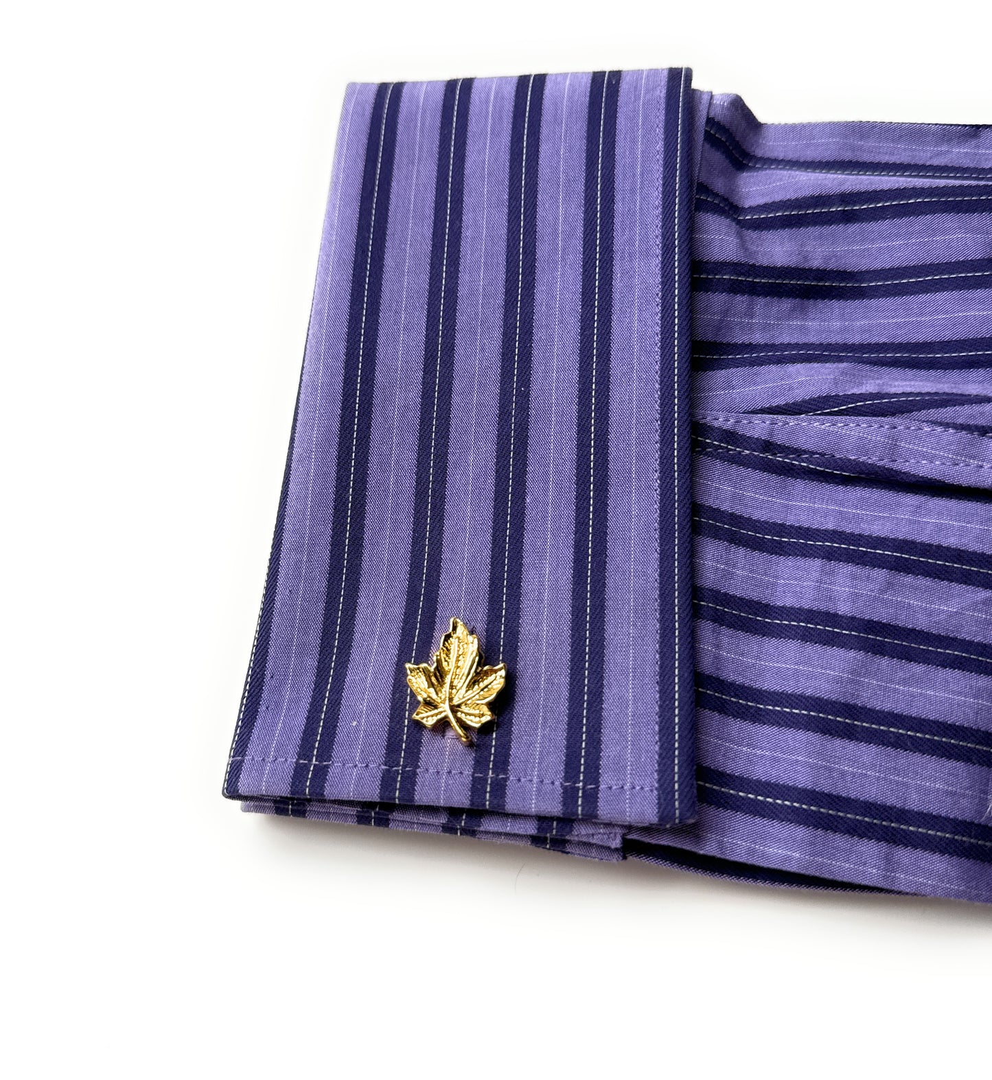 Purple striped shirt with a gold maple leaf cufflink on a white background
