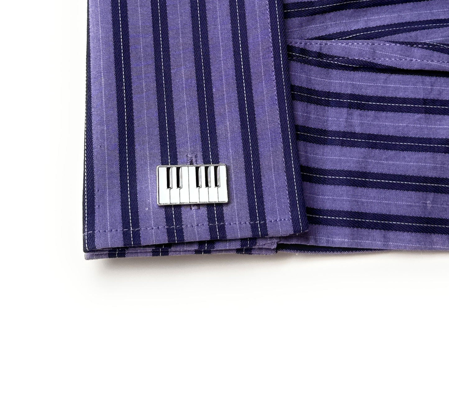 Purple striped fabric with a metal piano key cufflink on a white background