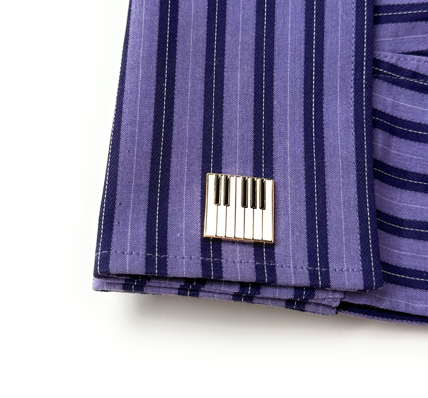 Close-up of a purple striped fabric with a metal tag on a white background