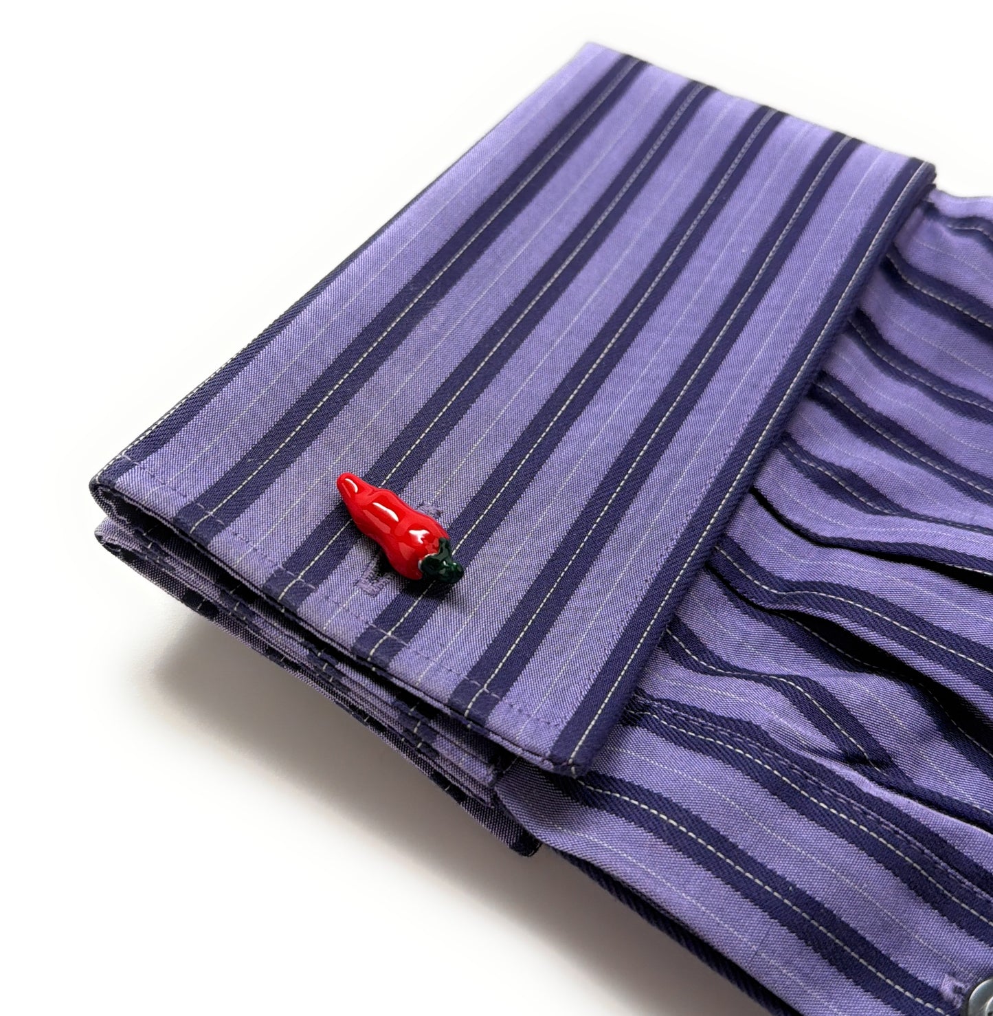 Folded purple striped fabric with a red and black decorative item on a white background