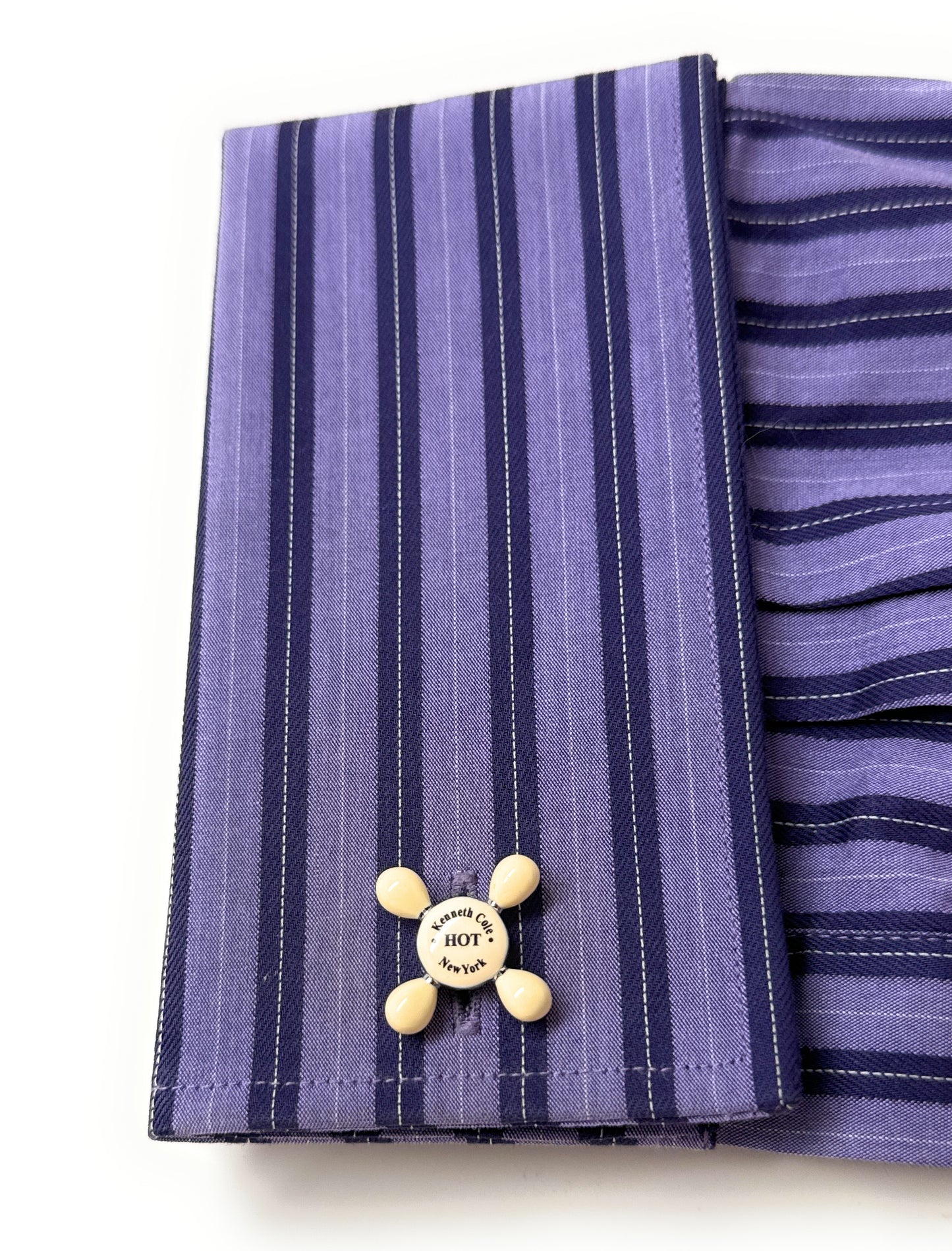 Purple striped fabric with a yellow button featuring text on a white background