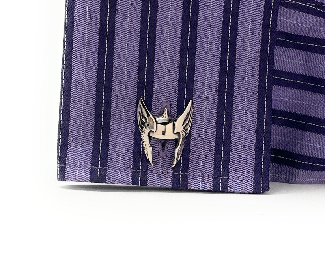 Close-up of a silver emblem on a purple striped fabric background
