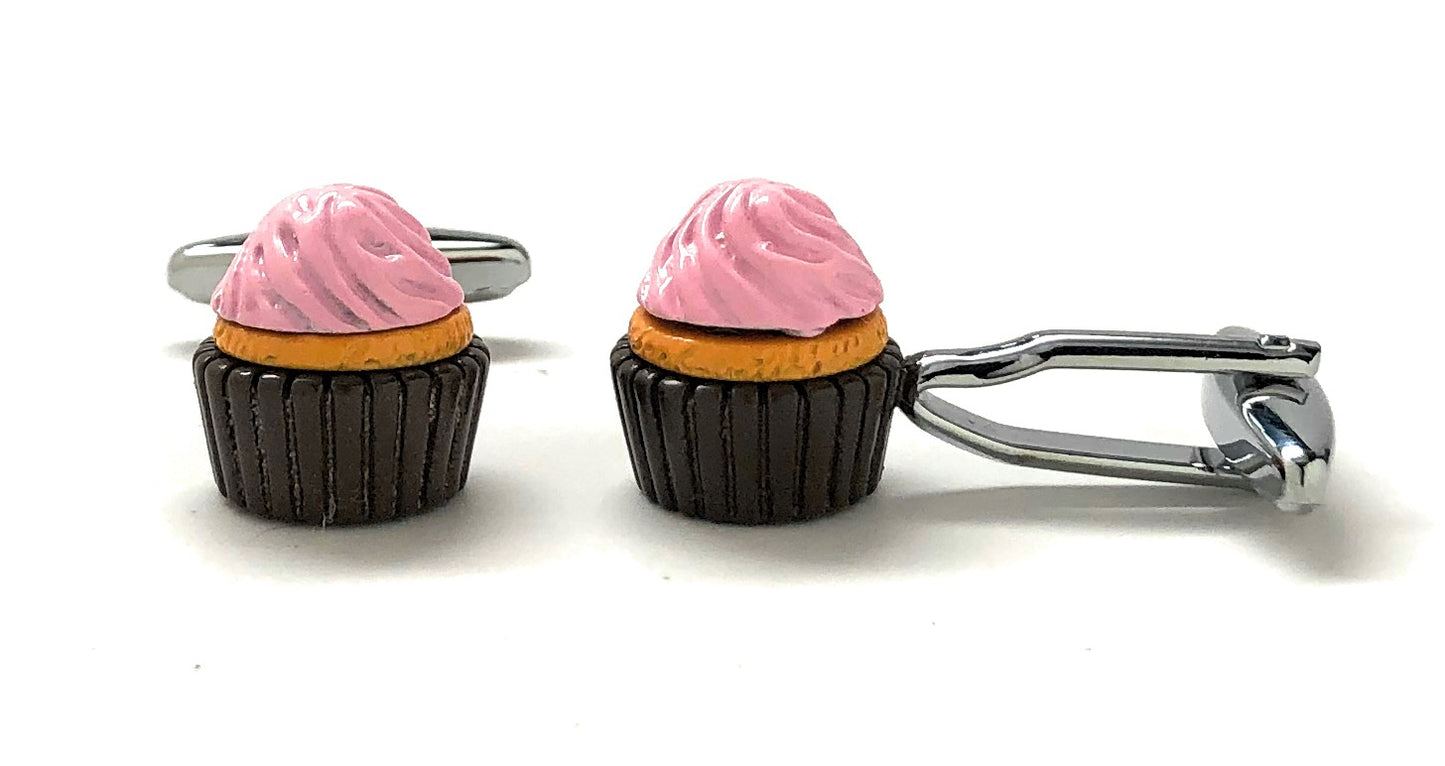Cupcake-shaped cufflinks with pink frosting and black bases on a white background