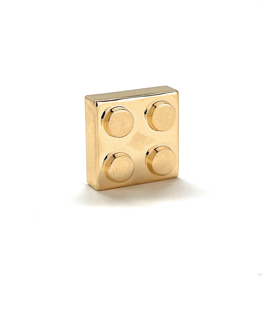 Gold square block with circular protrusions on a white background