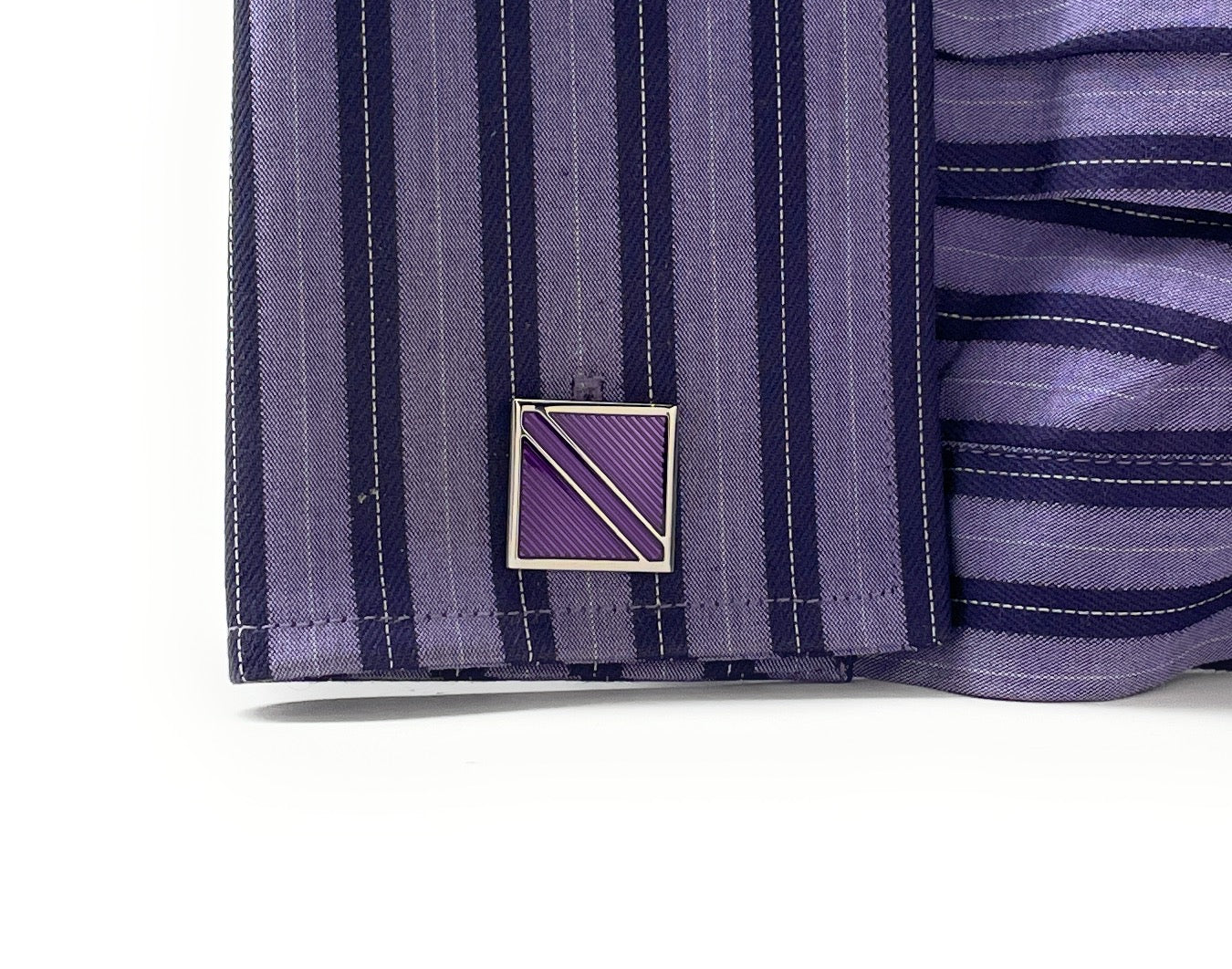Close-up of a purple striped shirt with a cufflink on a white background