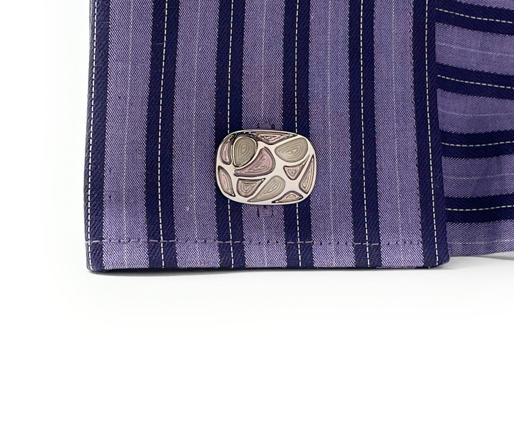 Close-up of a purple striped shirt with a decorative button on a white background