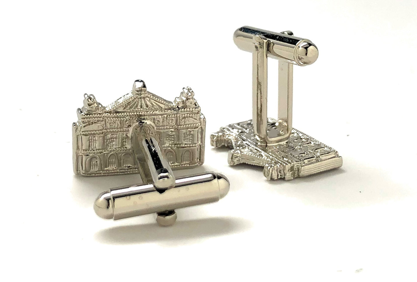 Silver cufflinks with detailed design on a white background