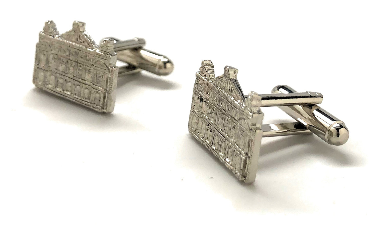Silver cufflinks shaped like a building on a white background