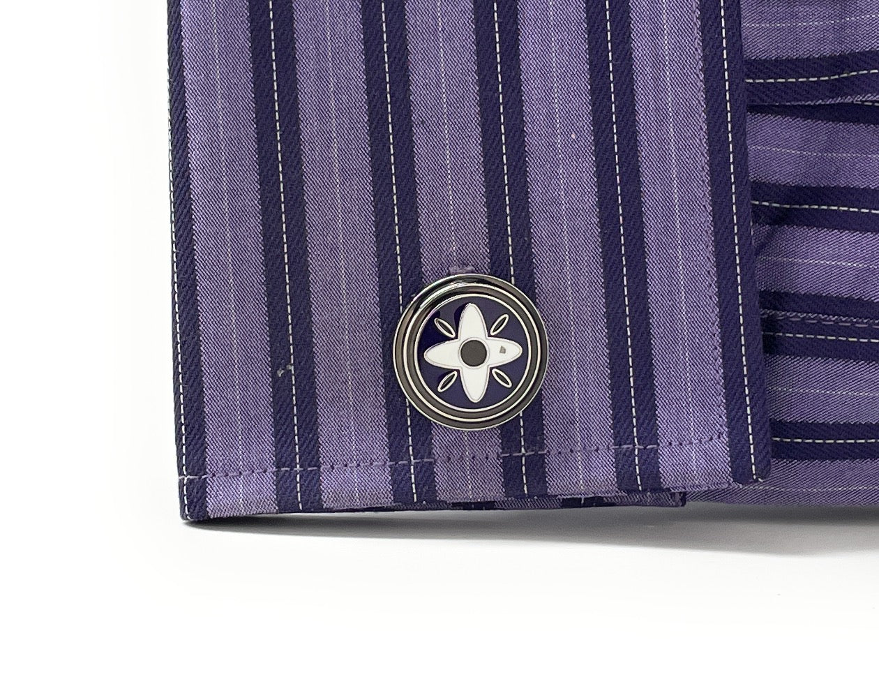Close-up of a purple striped shirt with a button featuring a white flower design on a white background